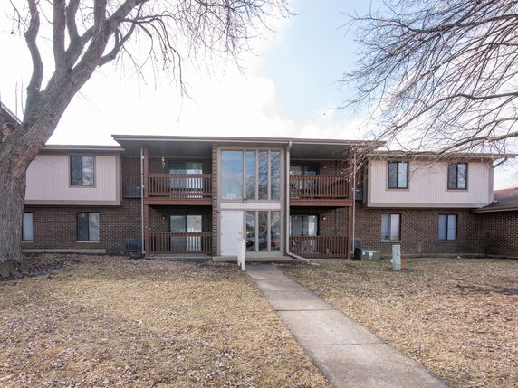 Front view of a two-story brick apartment building with balconies.