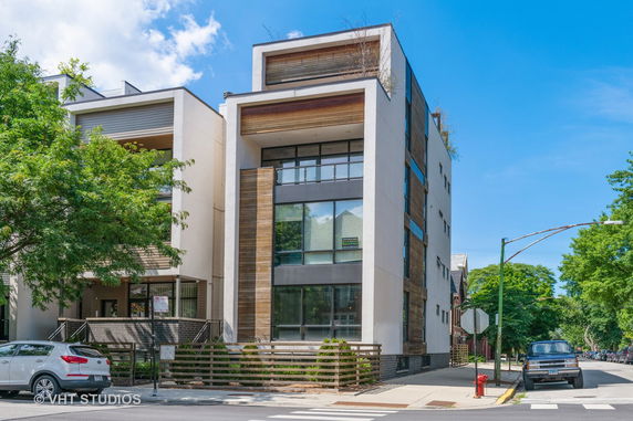 Front view of a modern multi-story building with large windows and a mix of wood and concrete facades.