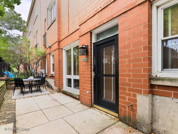 Front view of a brick townhouse exterior with a black door and several windows.