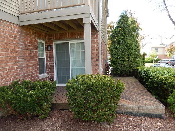Front view of a house featuring a patio with sliding glass doors and brick exterior.