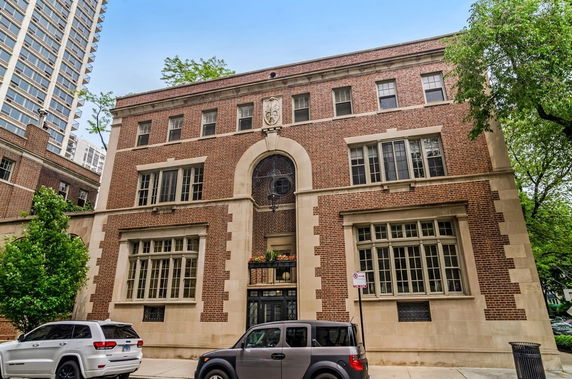 Front view of a multi-story brick building with large windows and decorative stone elements.