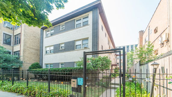 Front view of a multi-story brick building with a gated entrance.