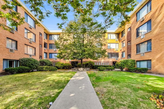 Front view of a multi-story brick apartment building with multiple windows.