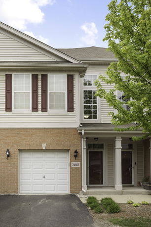 Front view of a two-story house with a garage and columned entrance.