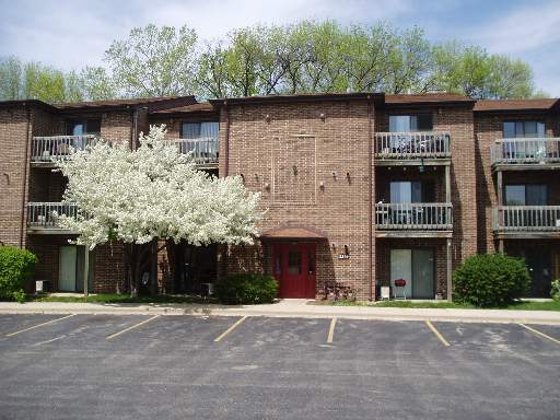 Front view of a three-story brick apartment building with balconies.