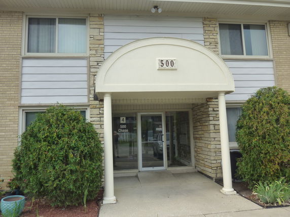 Front view of a building entrance with an arched canopy and two pillars.