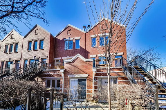 Front view of a two-story brick townhouse with external staircases.