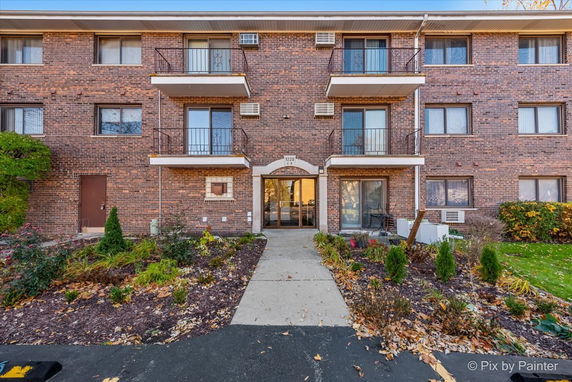 Front view of a multi-story brick building with balconies and large windows.