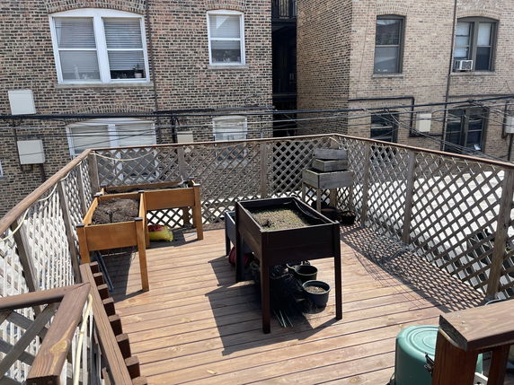 Rooftop deck with planters and lattice railing in an urban setting.