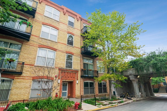 Front view of a multi-story brick apartment building with balconies.