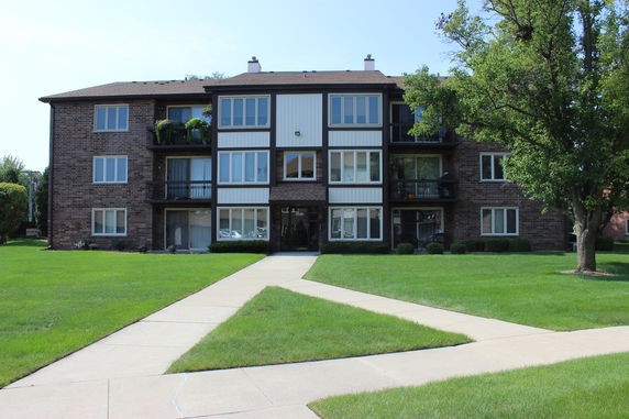 Front view of a multi-story residential building with balconies and large windows.