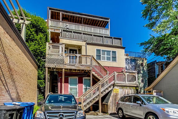 Front view of a multistory house with wooden balconies and exterior stairs.