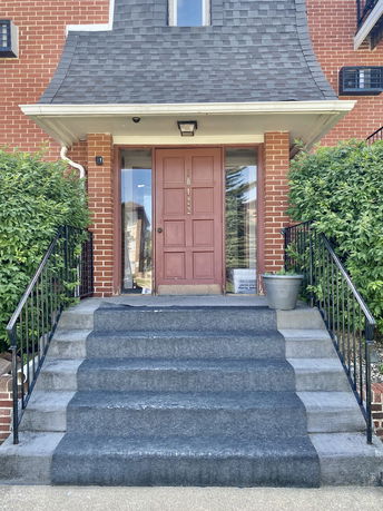 Front view of a brick house with entrance steps leading to a wooden door.