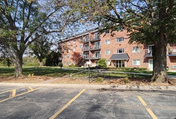 Front view of a multi-story brick apartment building with balconies.