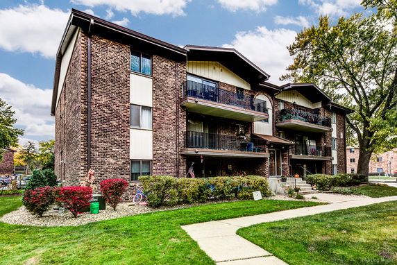 Front view of a multi-story brick apartment building with balconies.