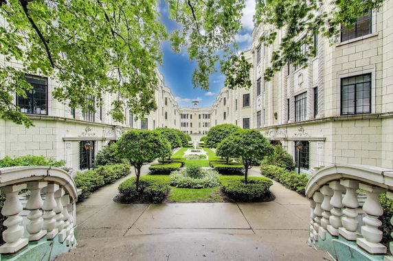 Front view of a multi-story stone building with decorative architectural elements and a courtyard.