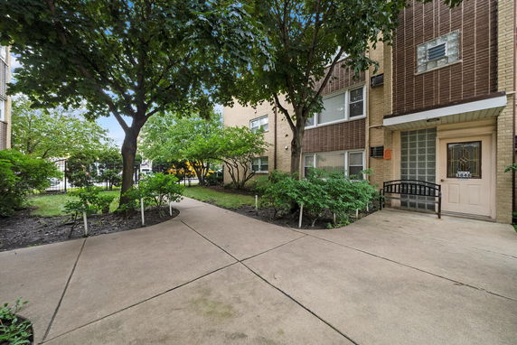 Front view of a multi-story building with an entrance and surrounding greenery.