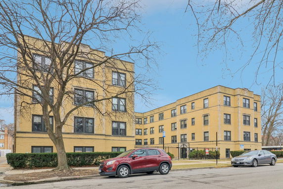Front view of a multi-story apartment building with a yellow brick exterior.