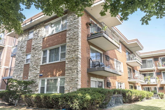 Front view of a multi-story brick apartment building with balconies.