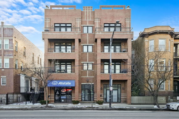 Front view of a multi-story brick building with balconies and a ground-floor business.