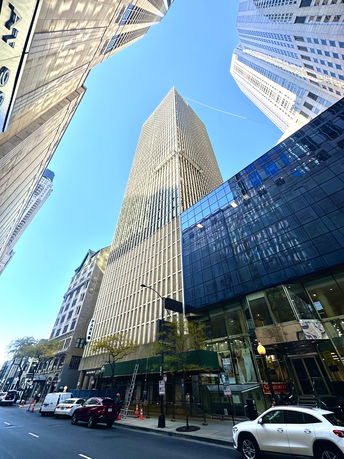 Front view of a tall multi-story building with glass facades in an urban setting.