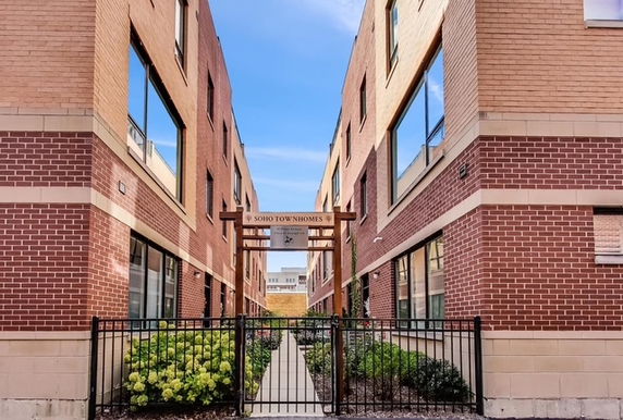 Front view of a brick townhome complex with a gated entrance.