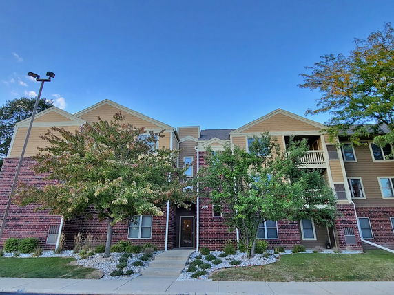 Front view of a multi-story brick and siding apartment building.