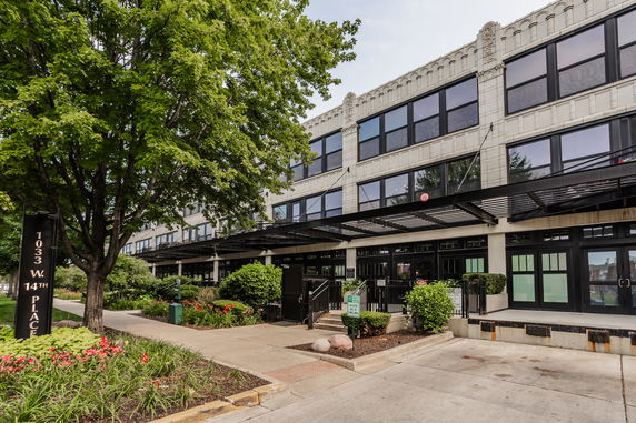 Front view of a multi-story commercial or residential building with large windows and a landscaped front area.