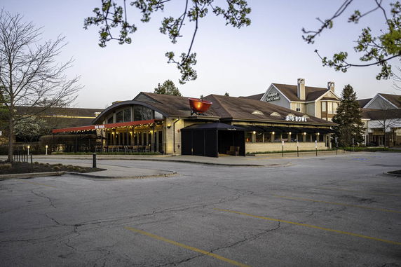 Front view of a commercial building with a rounded roof section and a red awning.