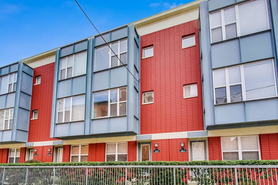 Front view of a modern multi-story residential building with colorful facade and large windows.