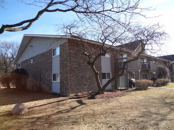 Front view of a two-story brick apartment building with balconies.