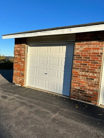 Front view of a garage with a brick exterior and white garage door.