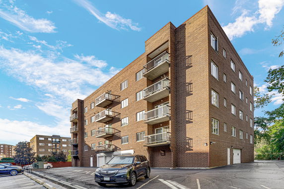 Front view of a multi-story brick apartment building with balconies.