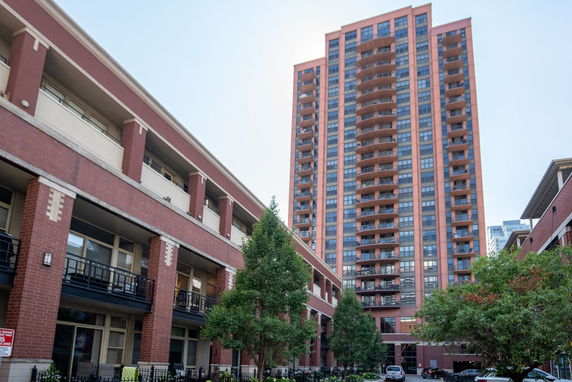 Front view of a tall apartment building with brick facade and balconies.