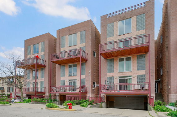 Front view of a modern multi-story building with balconies and a garage entrance.