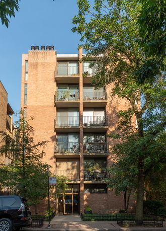 Front view of a multi-story brick apartment building with balconies.