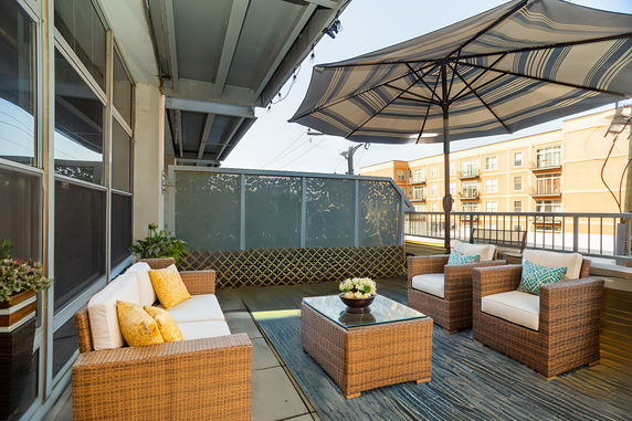Rooftop patio with wicker seating and large umbrella.