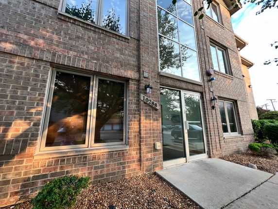 Front view of a brick building with large glass windows and a door.