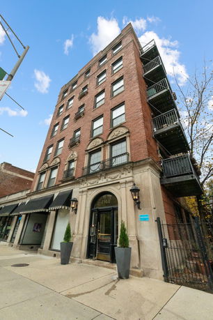 Front view of a multi-story brick building with decorative archways and black awnings.