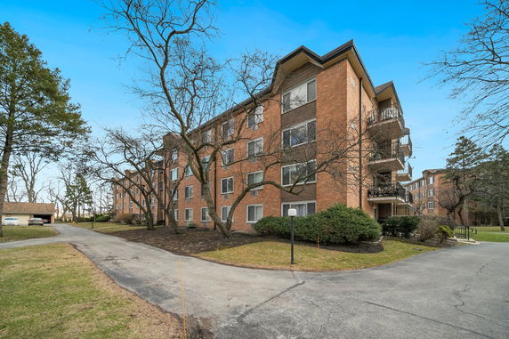 Front view of a multi-story brick apartment building with balconies.