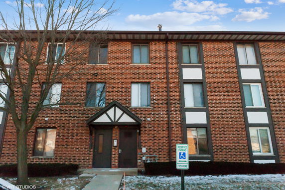 Front view of a three-story brick building with multiple windows and an entrance.