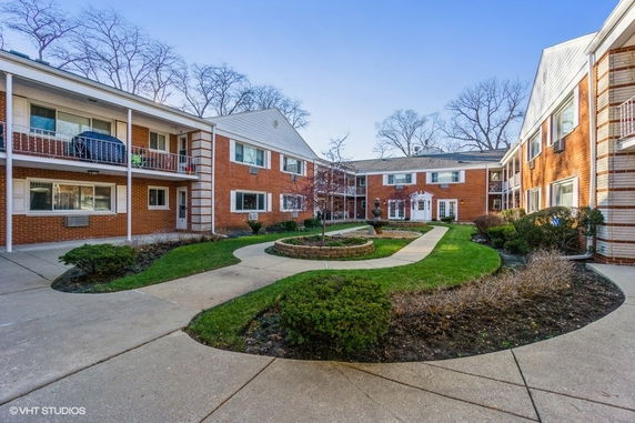 Front view of a brick apartment complex with two levels and a courtyard in the center.