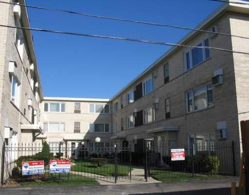 Front view of a multi-story apartment building with a gated entrance.