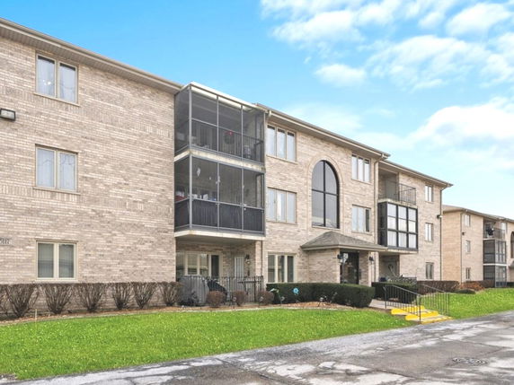 Front view of a multi-story brick apartment building with balconies.