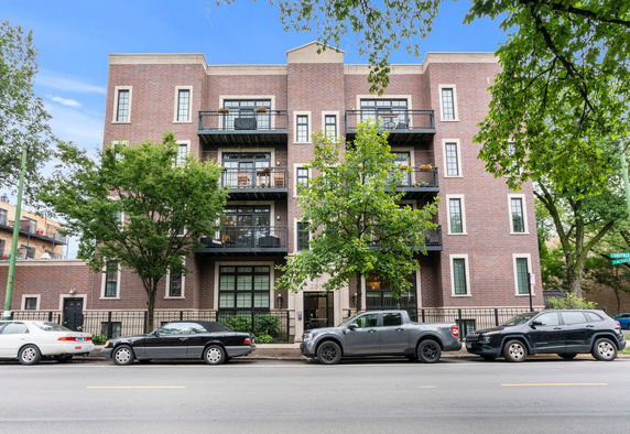 Front view of a multi-story brick apartment building with balconies.