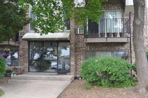 Front view of a multi-story brick building with balconies and a glass entrance door.