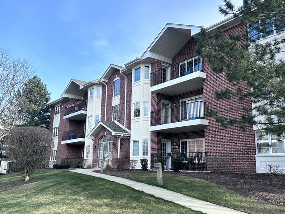 Front view of a three-story apartment building with brick and white facade.