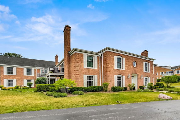 Front view of a two-story brick building with chimneys and white-trimmed windows.