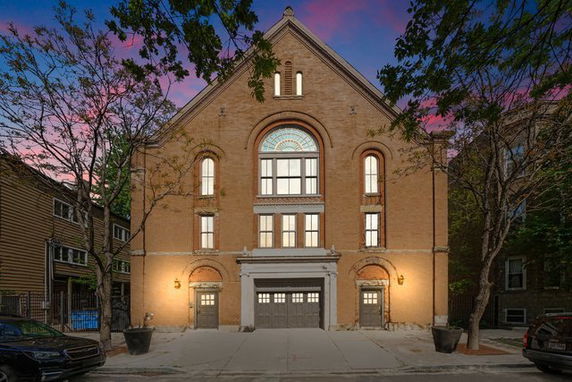 Front view of a brick building with large arched windows and a central garage entrance.