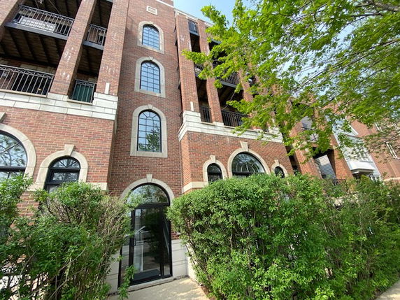Front view of a multi-story brick building with arched windows and balconies.